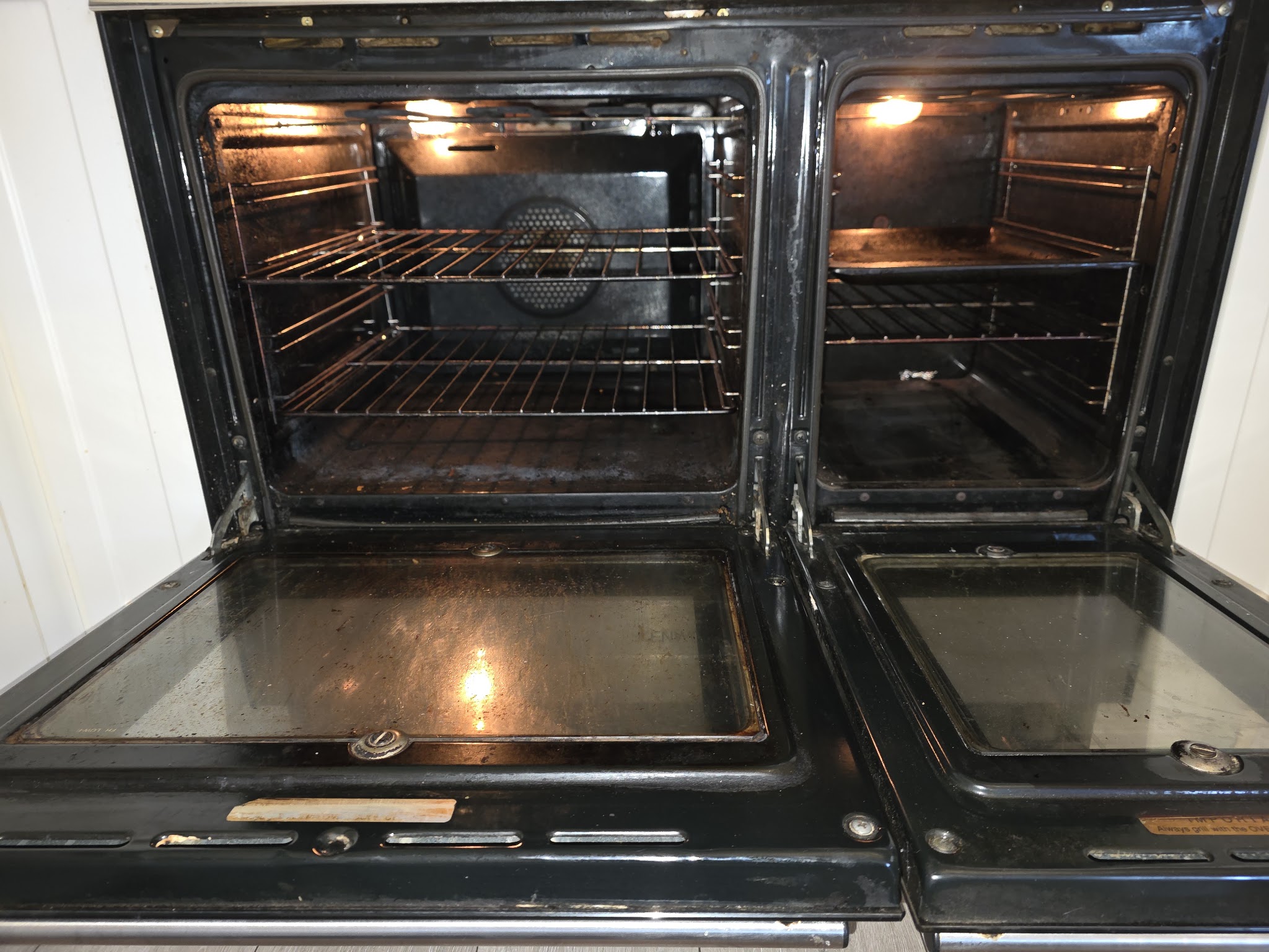 A black double range oven with both doors open, interiors and racks cleaned