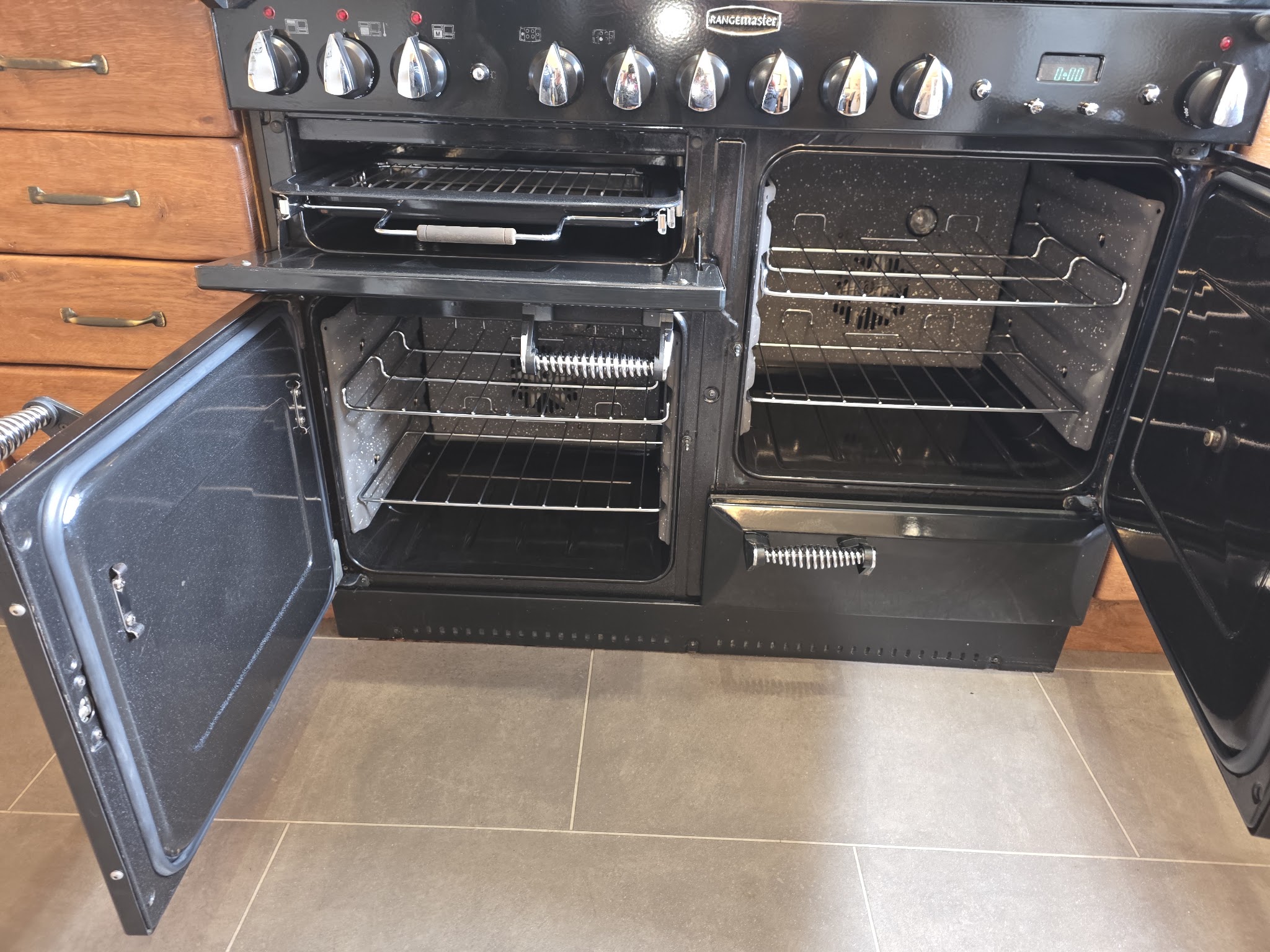 A black Rangemaster range cooker with every door open and clean shelves